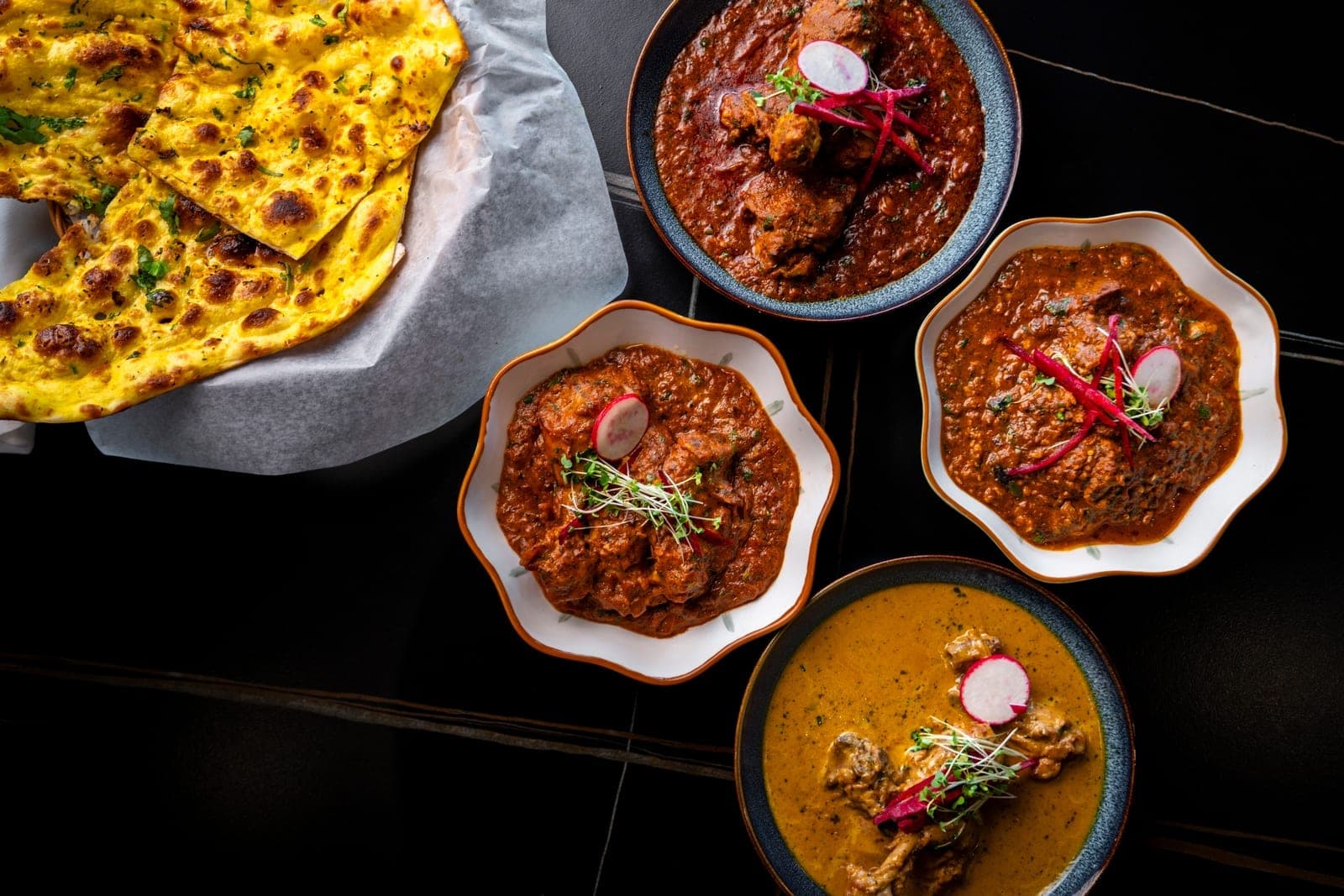 Overhead spread of curries and naan at DesINorth Milton — Indian restaurant in Milton, Ontario